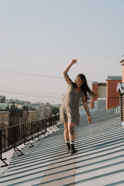 Woman in Brown Sleeveless Dress Standing on Black Metal Railings