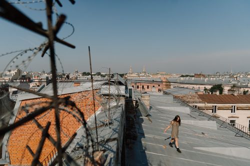 Free Woman walking on a rooftop with urban skyline background under clear blue sky. Stock Photo