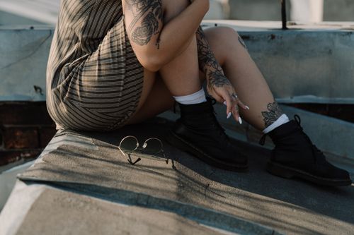 Free Tattooed woman relaxing on a rooftop with stylish black boots. Stock Photo