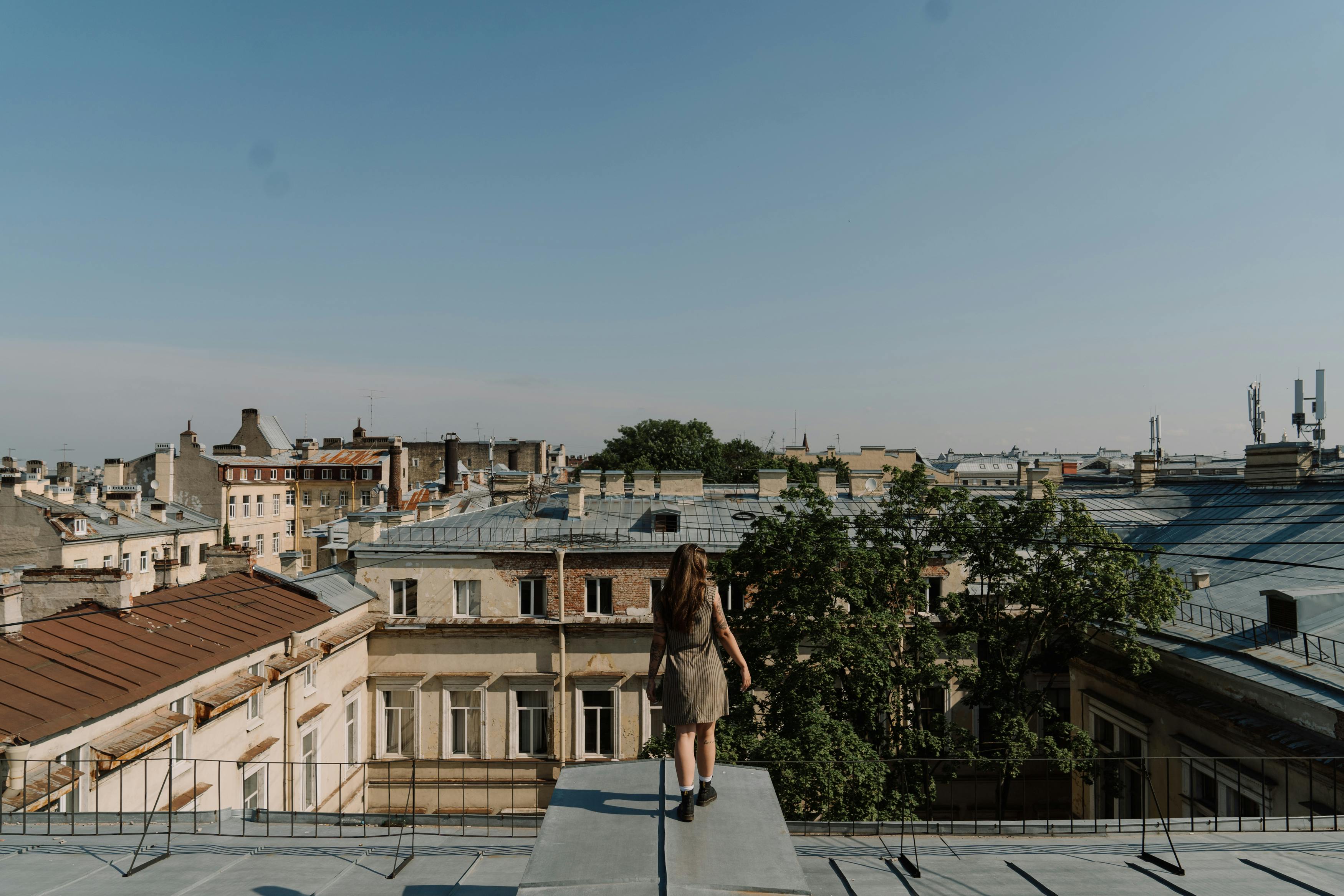 阳光明媚，一名女子站在屋顶上，凝望着古老的城市景观