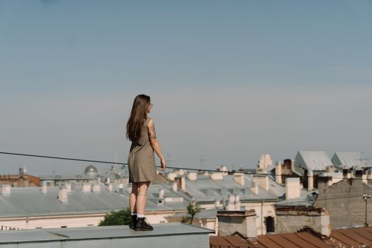 一名妇女站在屋顶上，凝视着蔚蓝天空下的城市景观