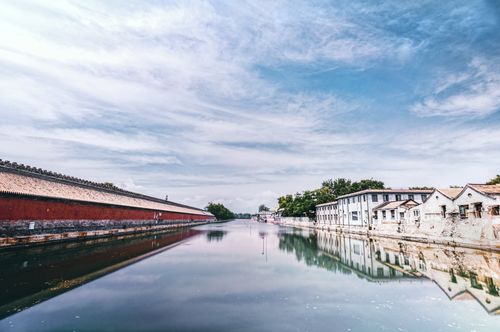Free A serene canal in Beijing reflecting adjacent historic architecture under a blue sky. Stock Photo