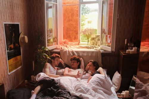 Free Three friends relaxing in a warm, inviting bedroom, sharing a moment. Stock Photo
