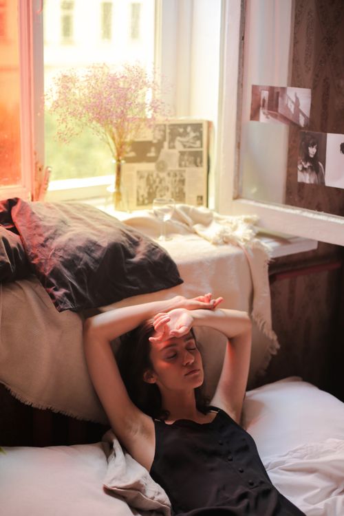 Free Woman in a dark room enjoying a quiet morning nap near a window. Stock Photo