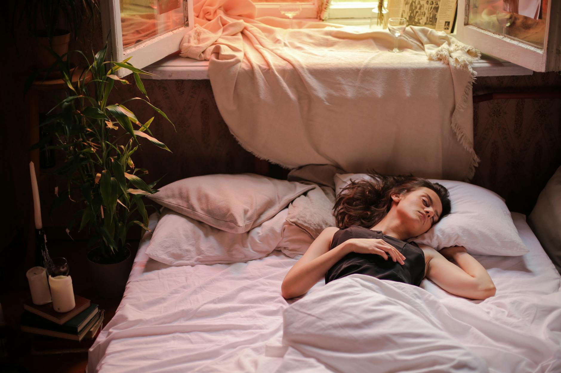 Woman in black tank top laying in white bed