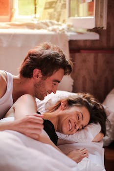 A joyful couple enjoying a cozy morning in bed with sunlight streaming in.