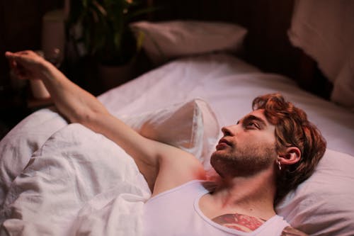 Man in White Tank Top Lying on Bed
