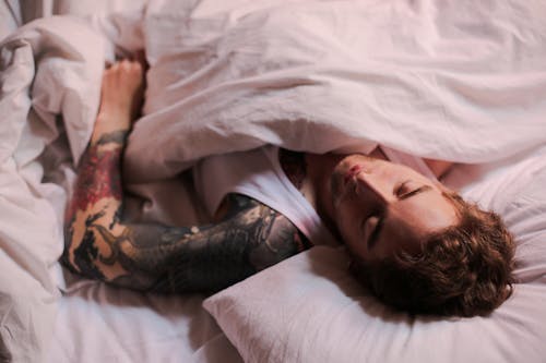 Free Woman Lying on Bed With Tattoo on Her Body Stock Photo