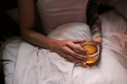 Person Holding Clear Glass Mug With Brown Liquid