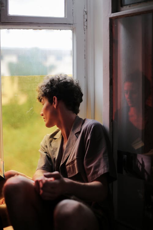 Free Man in Gray Button Up Shirt Sitting Beside Window Stock Photo