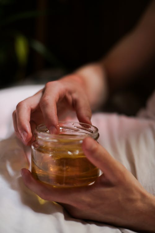 Person Holding Clear Drinking Glass With Brown Liquid