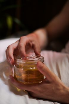 特写镜头：一只手持着装满蜂蜜的玻璃罐，室内场景，灯光柔和