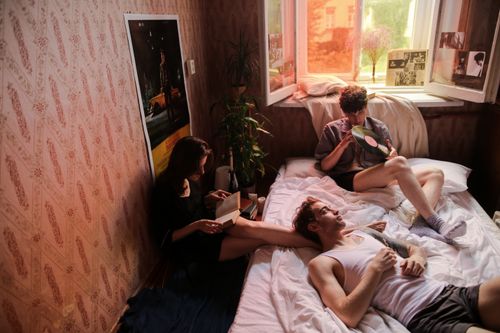 Free Three friends relaxing in a cozy bedroom, reading and listening to vinyl records. Stock Photo