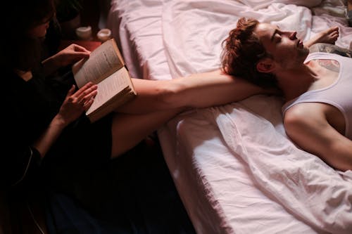 Free Woman Lying on Bed Reading Book Stock Photo