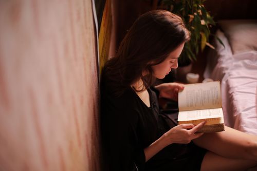 Free A young woman reading a book indoors, enjoying leisure time and relaxing in her cozy apartment. Stock Photo
