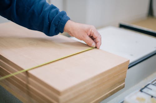 A Person Measuring a Wood Plank