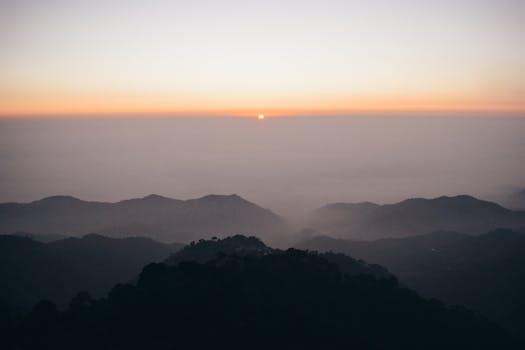 Breathtaking sunset over misty mountain ranges, capturing nature's serene beauty and tranquility.