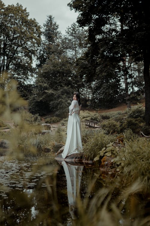 Woman in White Wedding Dress Standing Near River