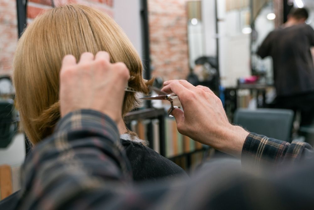 Coiffeuse réalisant une coupe en salon