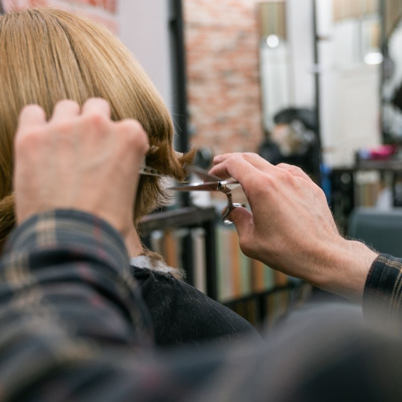 Stylist trimming blonde hair in a salon