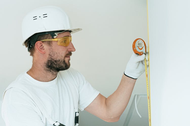 A Man With A Hard Hat Holding A Measuring Tape