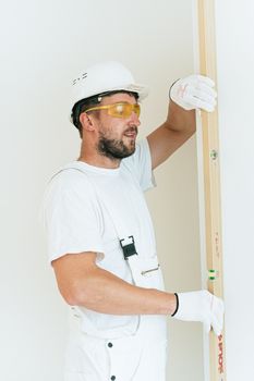 木匠穿着安全装备，在室内使用水平杆进行精确的施工工作