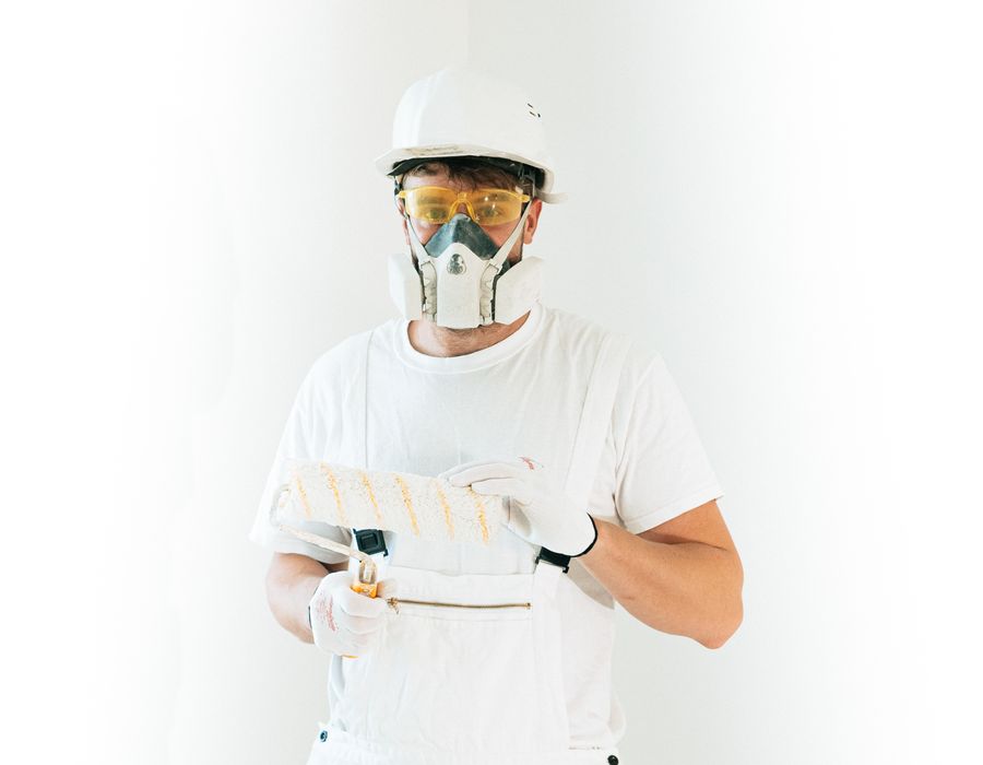 Profissional de pintura com equipamento de proteção e rolo