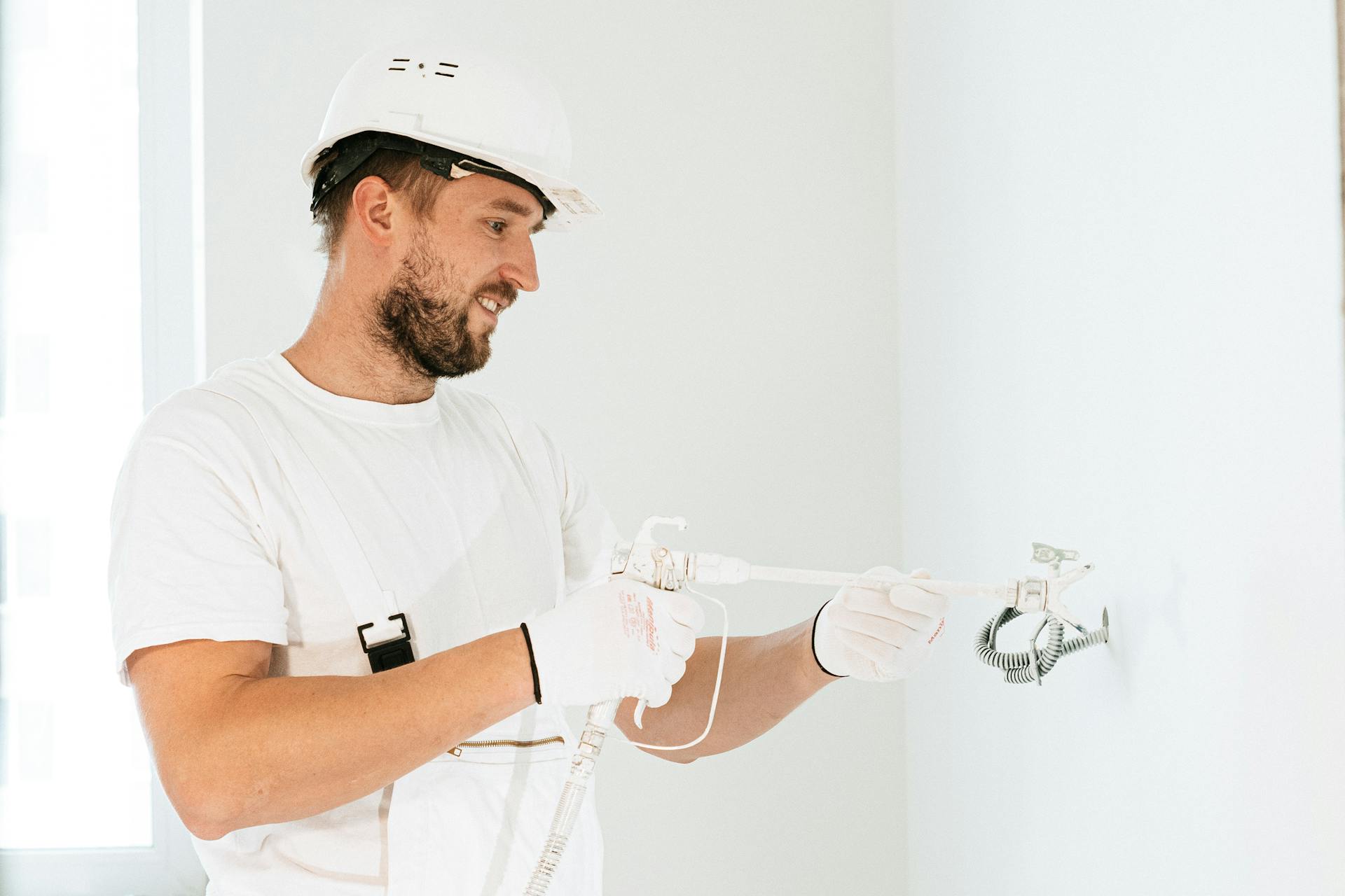 Electrician wearing safety gear installing wiring in a new building.