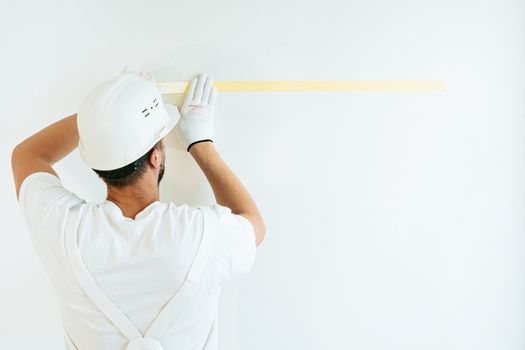 建筑工人在墙上贴胶带，准备涂漆或测量