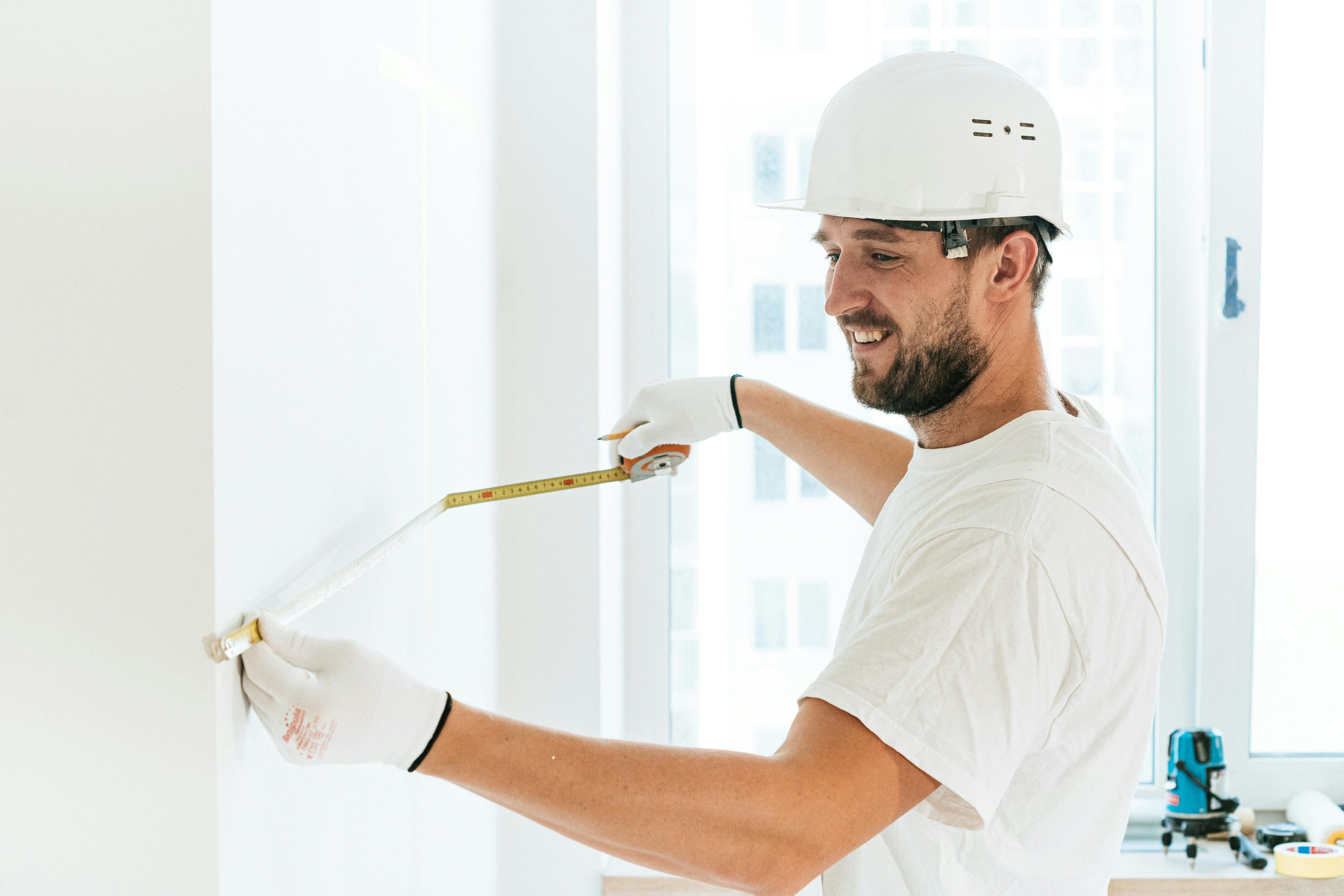 man in white crew neck t shirt wearing white cap holding white paint brush