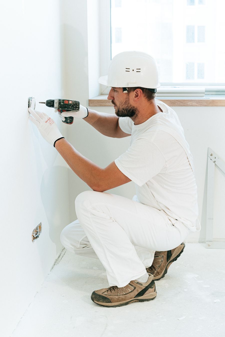 Professional tradesperson using a drill during an indoor wall installation