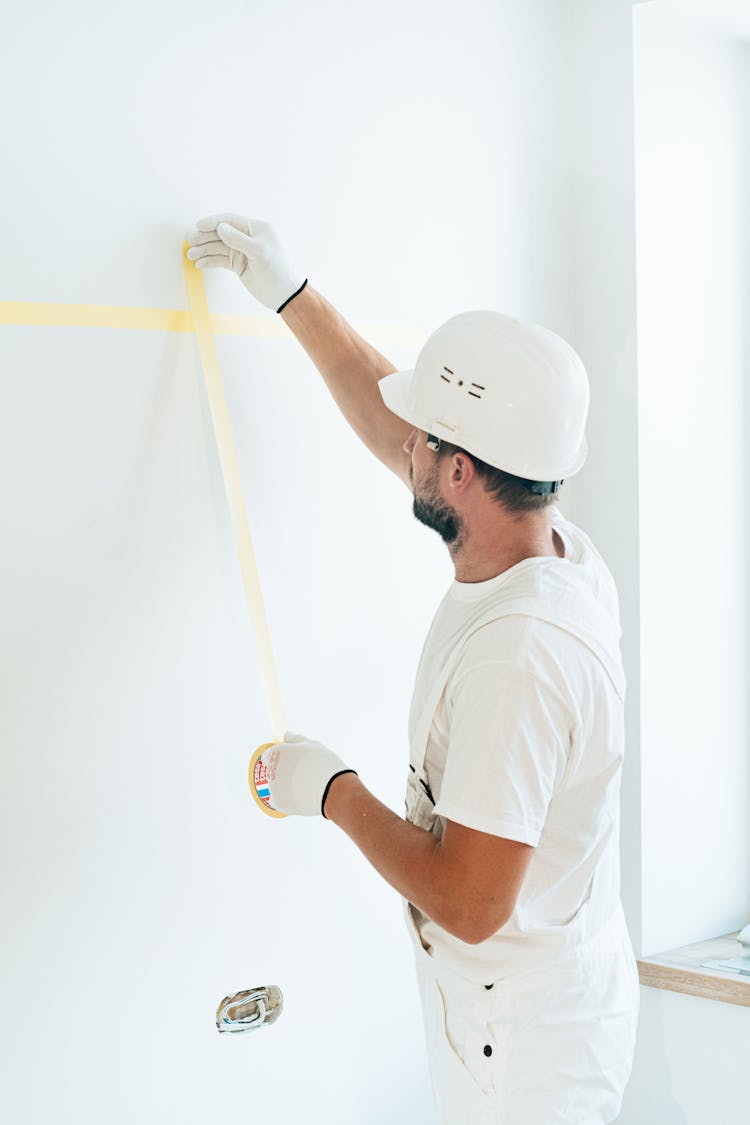 A Man Putting Tape On The Wall