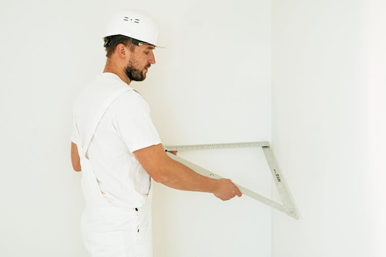 A Man Measuring A Wall