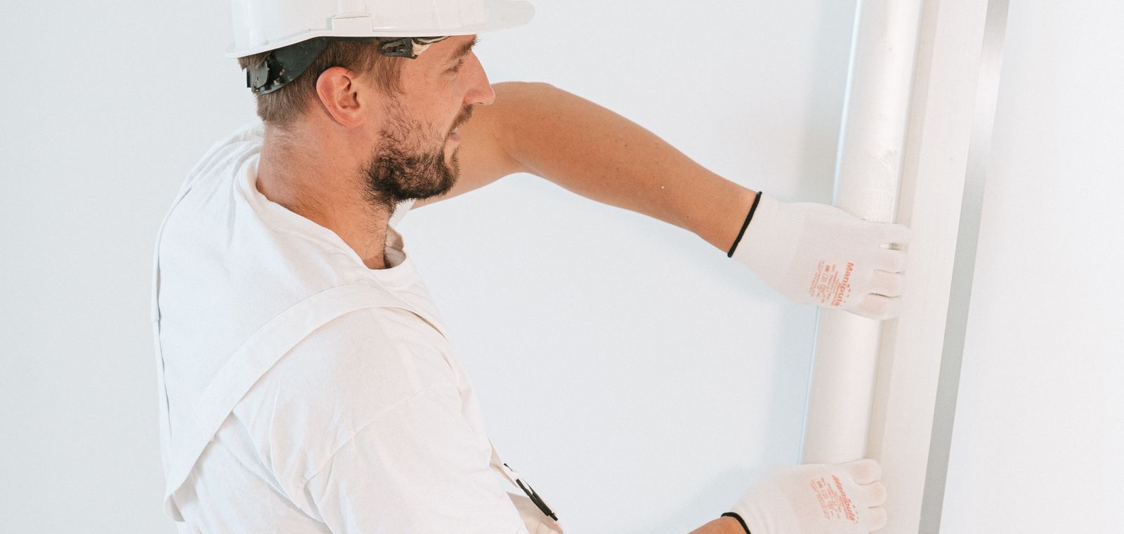 Worker in gloves and helmet installing drywall