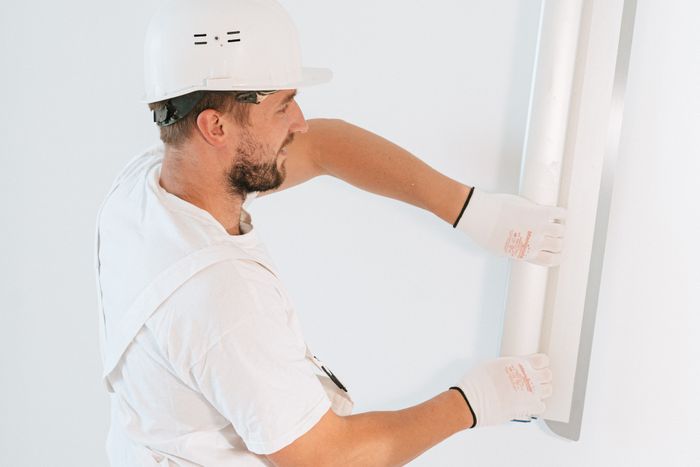 Trockenbauer setzt ein Eckprofil an die Wand