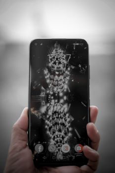 Crop hand of unrecognizable person holding smartphone with screensaver in hand against blurred background