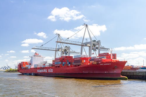 Free A Red Cargo Ship with Harbour Cranes Stock Photo