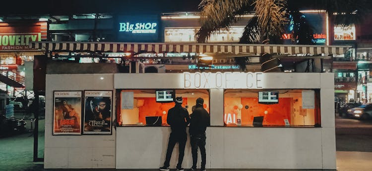 Men Buying Tickets In A Box Office 