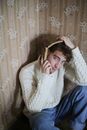 室内，一个年轻人顽皮地戴着书，穿着毛衣和牛仔裤