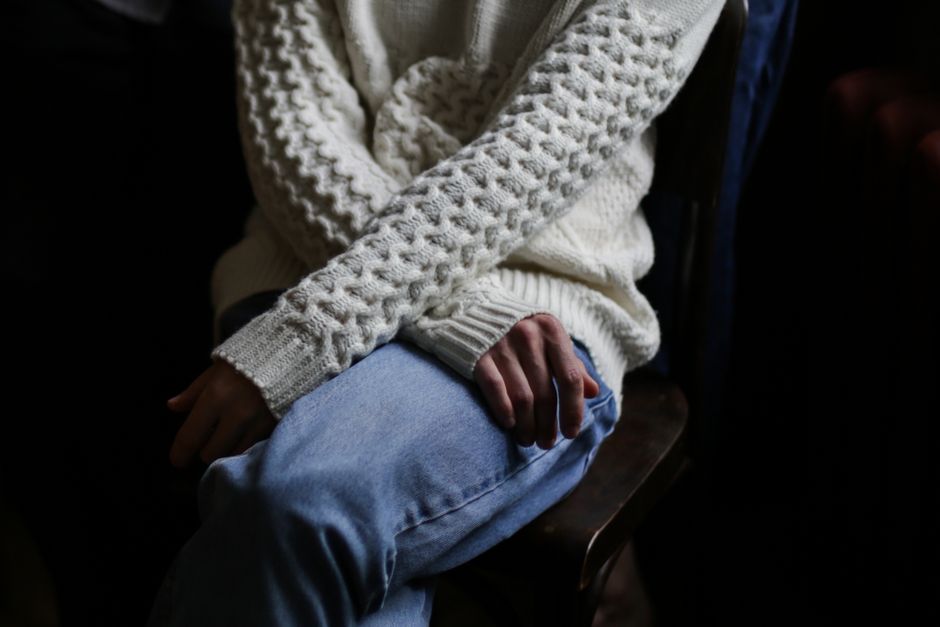 Detailed close-up of a person sitting in a cozy white sweater and blue jeans.