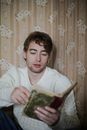一位穿着毛衣的白人男子在贴着复古壁纸的室内阅读肖像