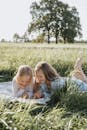 两个年轻的女孩在阳光明媚的草地上，坐在毯子上读一本书