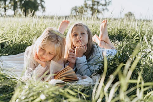 Free Little Girls Lying on Green Grass Field Stock Photo