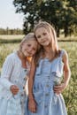 阳光明媚的户外田野里，两个年轻的姐妹微笑着摆姿势，表达着喜悦和温暖