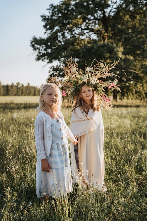 Little Girls Standing on a Grass Field