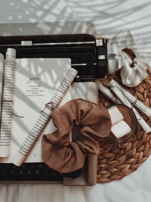 A creative flat lay of a vintage typewriter surrounded by paper rolls and scrunchies, set against a woven background.