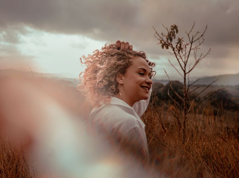 Femme souriante et épanouie en pleine nature au coucher du soleil