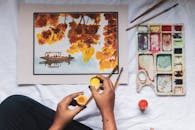 Faceless painter with bright paint near artwork on creased sheet