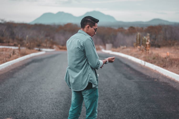 Man Standing On An Asphalt Road In The Middle Of Nowhere