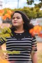Woman in Black and White Striped Shirt Standing Near Green and Yellow Leaves